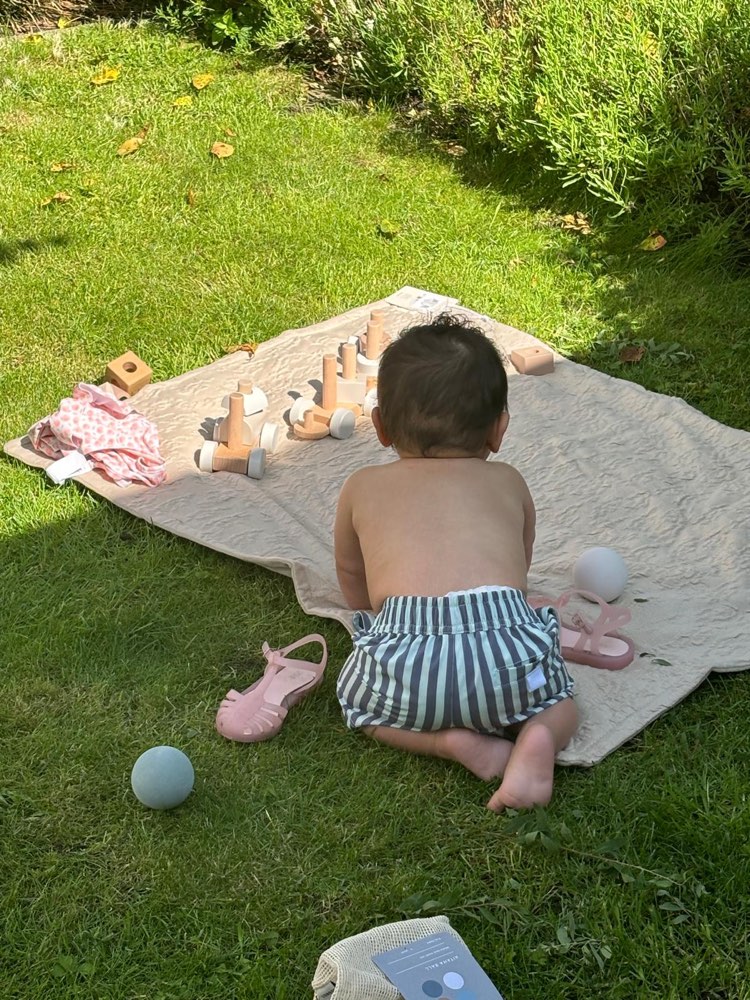 Spelen met houten speelgoed op een kleed in de tuin.