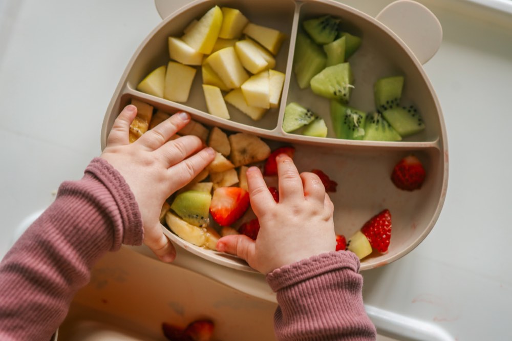 Vers gesneden fruit op een kinderbordje, klaar voor het eetmoment.