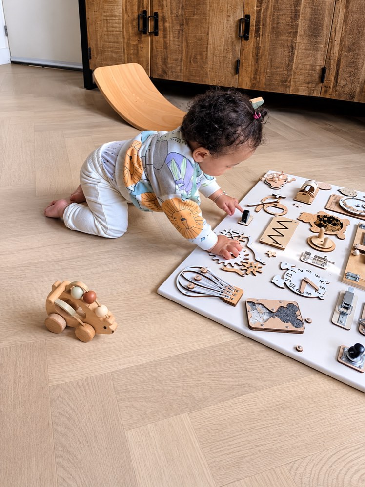 Ontdekken met een houten activiteitenbord in de speelruimte.
