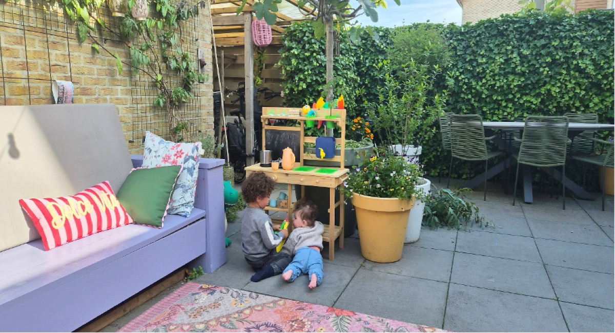Kinderen spelen bij de modderkeuken in de tuin.
