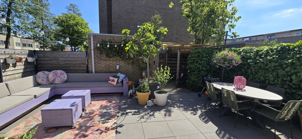 Ruime tuin met loungehoek en planten om buiten te spelen.